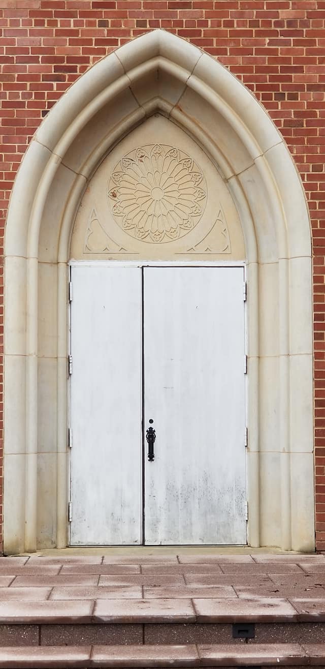 A white door with two windows and a red brick wall.