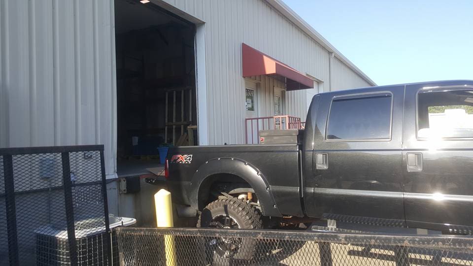 A truck parked in front of a building with a large door.