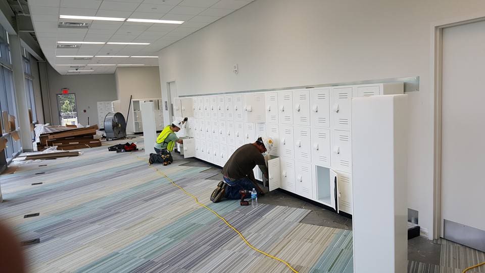 Two men working on a wall in an office.